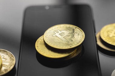 Masasında bir sürü bozuk para olan akıllı bir telefon üzerinde altın bitcoin para. Sanal kripto para birimi kavramı. Sanal para madenciliği çevrimiçi işyeri. Bitcoin ticareti.