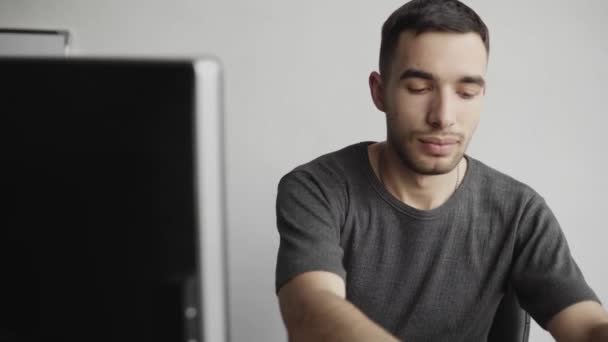 Young man start using virtual reality goggles headset and sitting in the office against computer. Connection, technology, new generation. Man trying to touch objects or control VR with a hand. — Stock Video