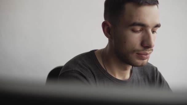 Young man start using virtual reality goggles headset and sitting in the office against computer. Connection, technology, new generation. Man trying to touch objects or control VR with a hand. — Stock Video