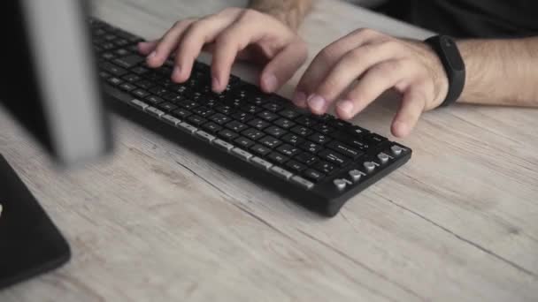 Zakenman student of freelancer in een shirt zit tegen monitor van de computer en typt een toetsenbord aan een tafel in het kantoor. Werken aan zijn laptop op kantoor. — Stockvideo