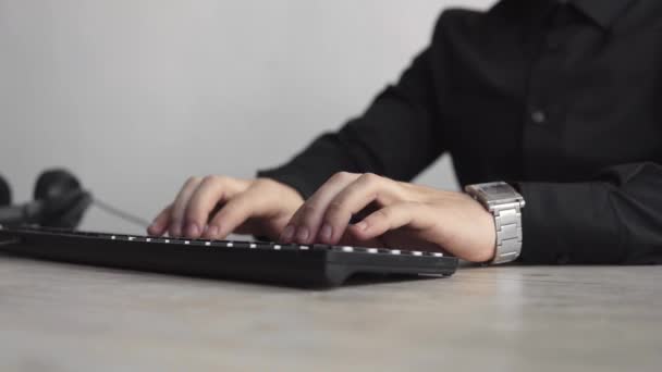 Jovem homem de negócios ou estudante em uma camisa que se senta contra o monitor do computador. Trabalhando em um PC em uma mesa no escritório com uma expressão pensativa. Jovem empresário trabalhando em seu laptop no escritório . — Vídeo de Stock