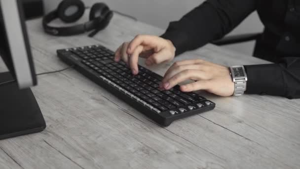 Uomo d'affari giovane o studente in una camicia che si siede contro monitor di computer. Lavorare su un pc a un tavolo in ufficio con un'espressione premurosa. Giovane uomo d'affari che lavora sul suo computer portatile in ufficio . — Video Stock