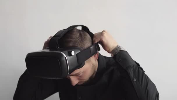 Młody brodaty mężczyzna zaczyna używać zestawu słuchawkowego VR siedzącego na komputerze i próbującego czegoś dotknąć lub stuknąć coś przed tym, co widzi. Nowoczesne technologie. Koncepcja przyszłej technologii. — Wideo stockowe