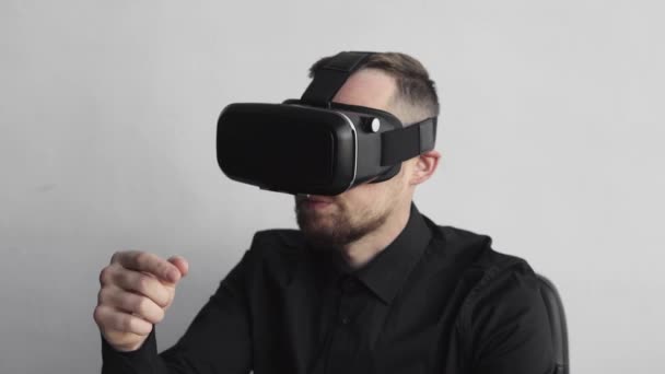 Young bearded man finish using vr headset sitting against computer and trying to touch something or tap some thing in front of what he seeing. Modern technologies. The concept of future technology. — Stock Video