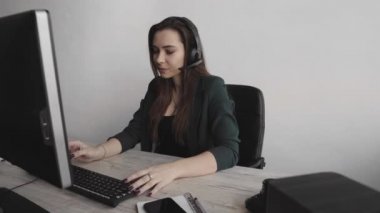 Genç esmer kadın servis operatörü ofisi arıyor. Genç müşteri destek müdürü sorulara kulaklıkla cevap vererek tüketiciye danışıyor. Gülümseyen iş kadını müşteri destek ajanı.