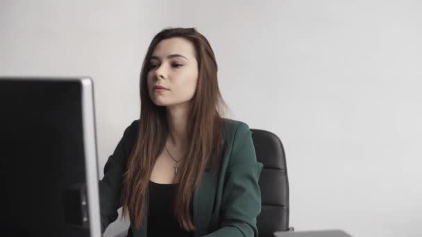 Mujer morena está trabajando delante de un monitor en una oficina. Mujer de negocios trabajando en la computadora en el espacio de coworking. Retrato de la señora feliz escribiendo en el lugar de trabajo. Profesional femenino trabajando con pc . — Vídeo de stock