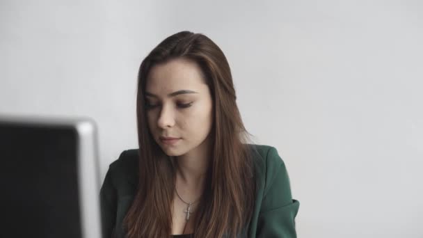 Brunette woman is working in front of a monitor in a office. Business woman working at computer at coworking space. Portrait of happy lady typing at workplace. Female professional working with pc. — Stock Video