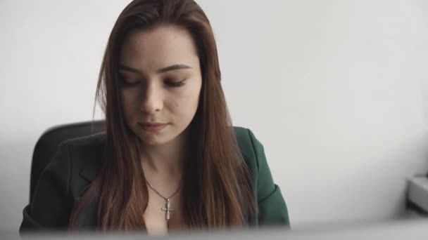 Brunette woman is working in front of a monitor in a office. Business woman working at computer at coworking space. Portrait of happy lady typing at workplace. Female professional working with pc. — Stock Video