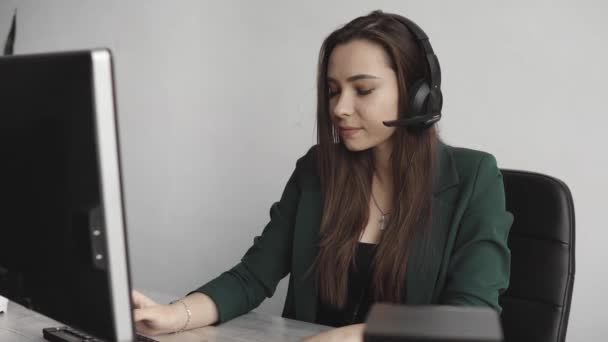 Η νεαρή Μπρουνέτ παίρνει τηλέφωνο στο γραφείο. Νέος διευθυντής υποστήριξης πελατών συμβουλεύεται τον καταναλωτή με ακουστικά απαντώντας σε ερωτήσεις. Χαμογελαστός πράκτορας υποστήριξης πελατών γυναίκα των επιχειρήσεων. — Αρχείο Βίντεο