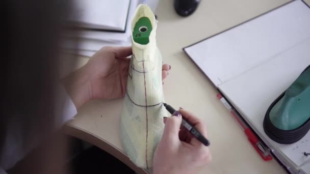 Modellierung Design eines Schuhs. Arbeitsplatz des Schuhdesigners. Designerhände zeichnen in seiner Werkstatt ein Schuhdesign auf einen neuen Schuh. — Stockvideo