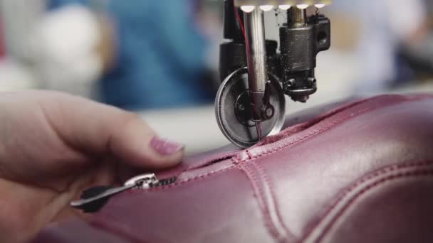 La máquina de coser en el taller de cuero en la acción con las manos que trabajan en los detalles de cuero para los zapatos. Macro tiro de las manos de las mujeres con máquina de coser en la fábrica de zapatos . — Vídeos de Stock