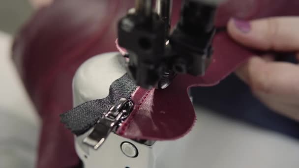 Machine à coudre dans un atelier de cuir en action avec des mains travaillant sur un détail en cuir pour chaussures. Macro shot de mains de femmes avec machine à coudre à l'usine de chaussures .