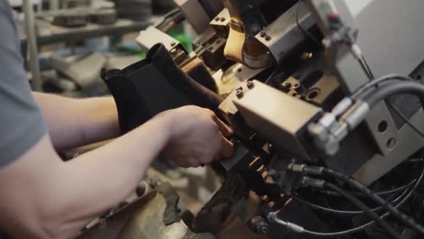 L'homme utilise une machine-outil spéciale pour fabriquer des chaussures. Le convoyeur sur une usine de chaussures avec chaussure et semelle. Production en série de chaussures . — Video