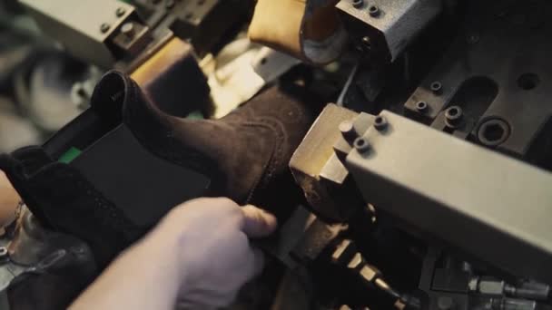 L'homme utilise une machine-outil spéciale pour fabriquer des chaussures. Le convoyeur sur une usine de chaussures avec chaussure et semelle. Production en série de chaussures . — Video