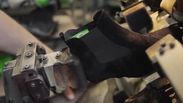 L'homme utilise une machine-outil spéciale pour fabriquer des chaussures. Le convoyeur sur une usine de chaussures avec chaussure et semelle. Production en série de chaussures . — Video