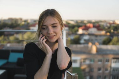 Genç bir iş kadını ofis binasının dışında akıllı cep telefonu kullanıyor ve iş ortaklarıyla konuşuyor. İş kadını telefona gülümseyerek cevap veriyor, iyi haberler alıyor. Serbest Çalışan.