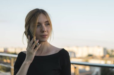 Genç bir iş kadını ofis binasının dışında akıllı cep telefonu kullanıyor ve iş ortaklarıyla konuşuyor. İş kadını telefona gülümseyerek cevap veriyor, iyi haberler alıyor. Serbest Çalışan.