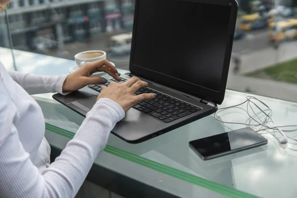 Una mujer está trabajando mediante el uso de una computadora portátil en la mesa. Manos escribiendo en un teclado. Mujer hombre de negocios está escribiendo en un teclado portátil sentado en la cafetería . — Foto de Stock