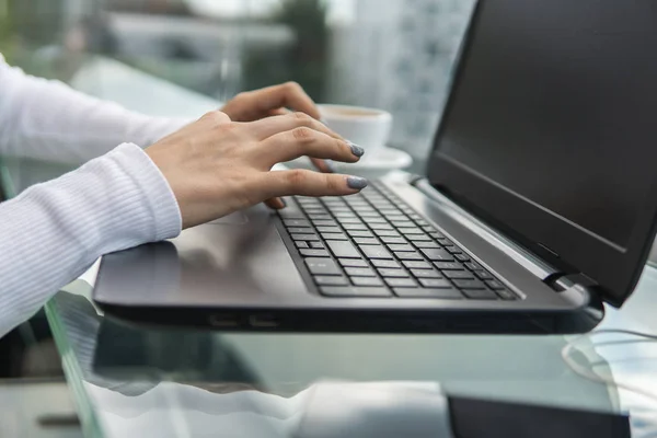 Una mujer está trabajando mediante el uso de una computadora portátil en la mesa. Manos escribiendo en un teclado. Mujer hombre de negocios está escribiendo en un teclado portátil sentado en la cafetería . — Foto de Stock