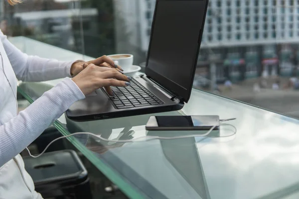 Una mujer está trabajando mediante el uso de una computadora portátil en la mesa. Manos escribiendo en un teclado. Mujer hombre de negocios está escribiendo en un teclado portátil sentado en la cafetería . — Foto de Stock