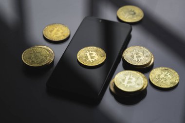 Masasında bir sürü bozuk para olan akıllı bir telefon üzerinde altın bitcoin para. Sanal kripto para birimi kavramı. Sanal para madenciliği çevrimiçi işyeri. Bitcoin ticareti.