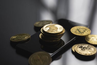 Masasında bir sürü bitcoin para olan akıllı bir telefon üzerinde altın Titan bitcoin yığını. Sanal kripto para birimi kavramı. Sanal para madenciliği çevrimiçi işyeri. Bitcoin ticareti.