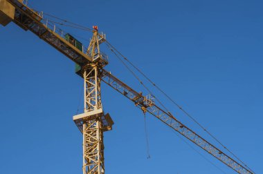 Çok katlı depolama ya da başka bir yapı için inşaat alanında mavi gökyüzüne karşı kule vinci.