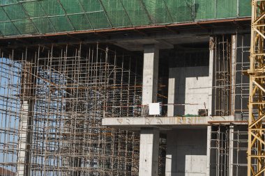 İnşaat ve İnşaat Alanı devam ediyor. Mavi gökyüzüne karşı inşaat alanı. Çok katlı bir depo inşaatı üzerine tamamlanmamış bir binanın metal yapısı.