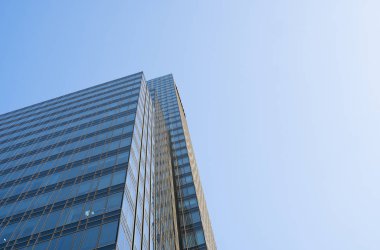 Bir binanın pencerelerinde gökyüzünün yansıması. Mavi gökyüzü üzerindeki modern cam bina gökdelenlerine bakış açısı ve görüş açısı yetersiz. İşyeri pencereleri ya da şirket binası.