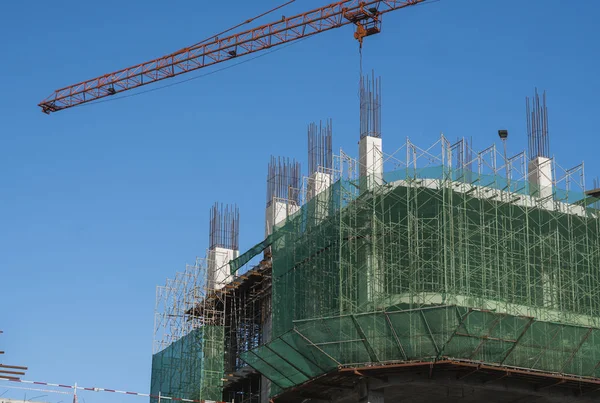 Kran und Baustelle vor blauem Himmel. Metallkonstruktion des Rohbaus auf dem Bau. Turmdrehkran-Einsatz für den Bau eines Mehrzweckgebäudes. — Stockfoto
