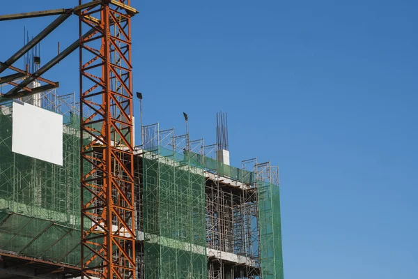 Mavi gökyüzüne karşı vinç ve inşaat alanı. İnşaatın bitmemiş binasının metal inşaatı. Crane kulesi çok katlı depo inşaatı için kullanılıyor. — Stok fotoğraf