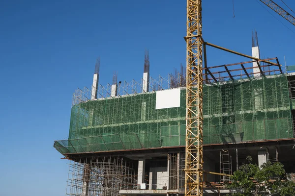 Mavi gökyüzüne karşı vinç ve inşaat alanı. İnşaatın bitmemiş binasının metal inşaatı. Crane kulesi çok katlı depo inşaatı için kullanılıyor. — Stok fotoğraf