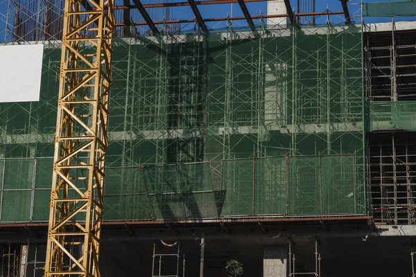 Kran und Baustelle vor blauem Himmel. Metallkonstruktion des Rohbaus auf dem Bau. Turmdrehkran-Einsatz für den Bau eines Mehrzweckgebäudes. — Stockfoto