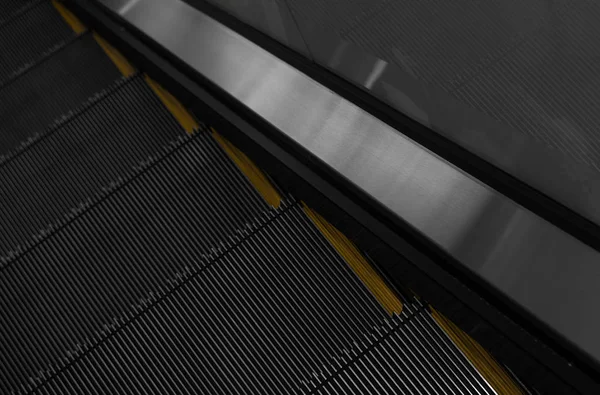 Moderno sistema electrónico de escaleras mecánicas en movimiento. Las escaleras mecánicas se están moviendo hacia arriba.El suelo es una línea recta. Negro con banda amarilla . — Foto de Stock