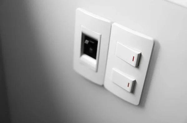 Interruptor blanco en una pared blanca con dos interruptores y un interruptor común . — Foto de Stock