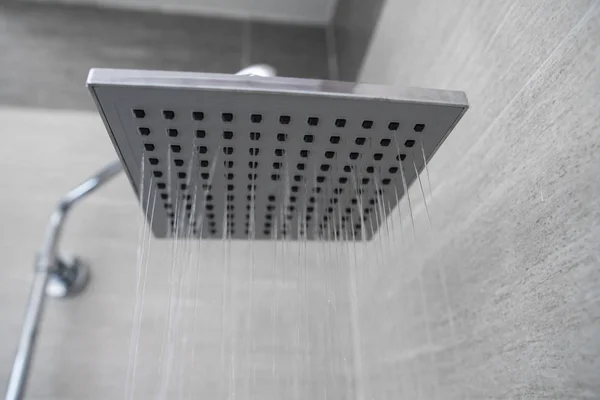 Vatten rinner från torget duschhuvud i ett modernt badrum. Dusch i badrummet med vattenspray eller vatten. En ström av sötvatten från duschmunstycket för att rengöra den smutsiga kroppen. — Stockfoto
