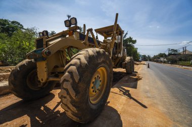 Grader yol inşaatında çalışıyor. Sınıf endüstriyel makine yeni yollar inşa ediyor. Otoyolda çalışan ağır iş makineleri. İnşaat malzemeleri. Yolun sıkıştırması.