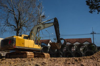 Büyük boruları bir araca aktarmak için kazıcı kullanmak.