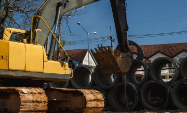 Büyük boruları bir araca aktarmak için kazıcı kullanmak.