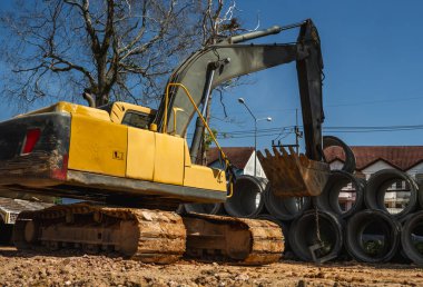 Büyük boruları bir araca aktarmak için kazıcı kullanmak.