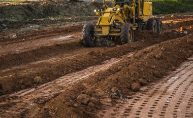 Grader yol inşaatında çalışıyor. Sınıf endüstriyel makine yeni yollar inşa ediyor. Otoyolda çalışan ağır iş makineleri. İnşaat malzemeleri. Yolun sıkıştırması.