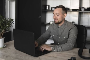 Happy Smile Genç işadamı veya öğrenci bilgisayar monitörü karşı oturan bir gömlek. Düşünceli bir ifade ile ofiste bir masada bir pc üzerinde çalışma.
