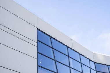 Bir binanın pencerelerinde gökyüzünün yansıması. Mavi gökyüzü üzerindeki modern cam bina gökdelenlerine bakış açısı ve görüş açısı yetersiz. İşyeri pencereleri ya da şirket binası.