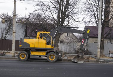Sarı kazıcı caddedeki bir yolun şantiyesinde duruyor. Ağır endüstri. Bir yol inşaatı.