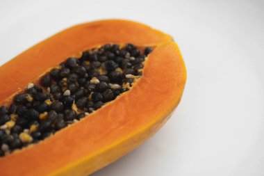 Beyaz bir tabakta tohum ile yarısı kesilmiş papaya. Beyaz arkaplanı olan tatlı papaya dilimleri. Yarım papayalar. Sağlıklı egzotik meyveler. Vejetaryen yemeği..