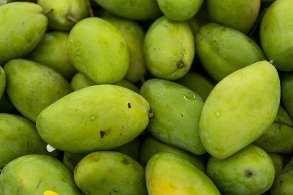 Textuur van groen sappig vers mangofruit. Groep van verse groene mango te koop .Thaise fruit tropische rauwe mango 's. Tropische en exotische vruchten. Gezonde en vitamine voedsel concept. — Stockfoto