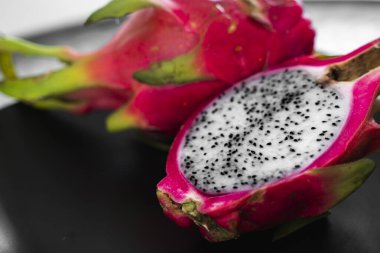 Ejderha meyvesi Siyah arka planda canlı Ejderha Meyvesi. Dilimlenmiş beyaz ejderha meyvesi ya da masa üzerindeki siyah tabakta pitaya, yakın plan. Tropikal ve egzotik meyveler. Sağlıklı ve vitaminli gıda kavramı.