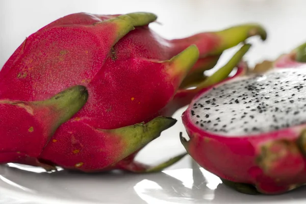 Fruta del dragón. Fruta del dragón vibrante sobre fondo blanco. Rebanadas de fruta de dragón blanco o pitaya en plato blanco en la mesa, de cerca. Frutas tropicales y exóticas. Concepto de alimentos saludables y vitamínicos . —  Fotos de Stock