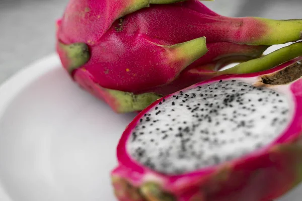 Frutto del drago. Vibrante Dragon Fruit su sfondo bianco. Fetta di frutta drago bianco o pitaya su piatto bianco sul tavolo, primo piano. Frutti tropicali ed esotici. Concetto di cibo sano e vitaminico . — Foto Stock