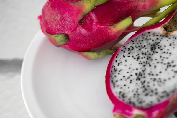 Drakfrukt. Vibrerande drake frukt på vit bakgrund. Skivad vit drake frukt eller pitaya på vit tallrik på bordet, närbild. Tropiska och exotiska frukter. Friska och vitamin livsmedel koncept. — Stockfoto